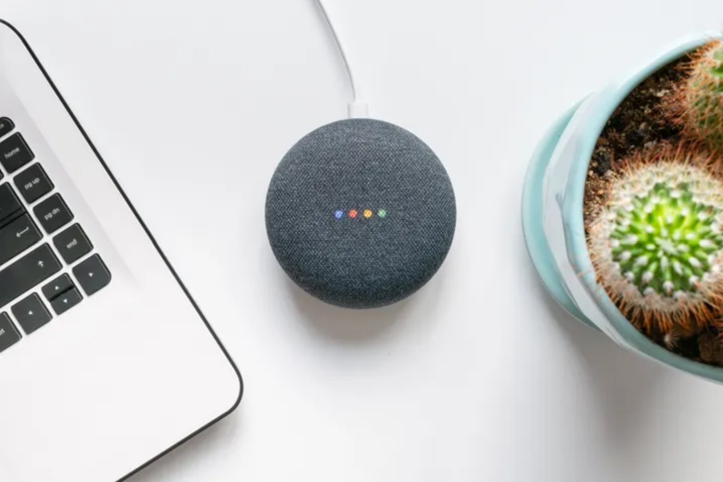 A photo of a charcoal grey Google Home Mini on a white desk